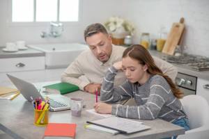 long-haired-girl-grey-shirt-her-father-doing-lessons-together_259150-6484